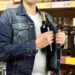 man in a supermarket stealing a bottle of champagne